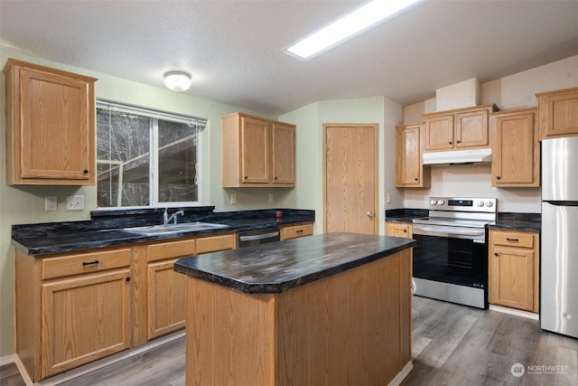 kitchen with sink, stainless steel appliances, a center island, wood-type flooring, and a textured ceiling