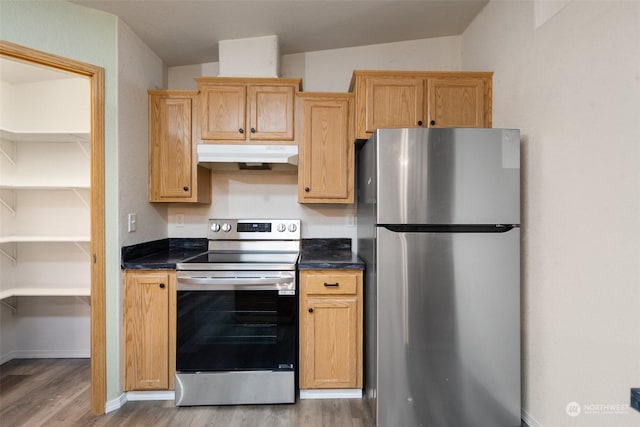 kitchen featuring lofted ceiling, appliances with stainless steel finishes, wood-type flooring, and light brown cabinets