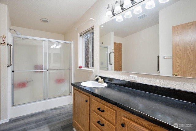 bathroom with hardwood / wood-style flooring, vanity, and a shower with shower door