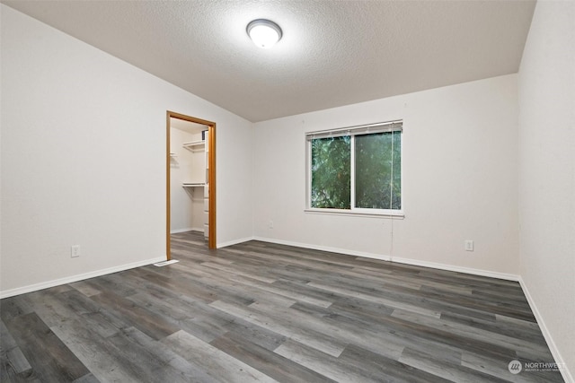 spare room with dark hardwood / wood-style flooring, lofted ceiling, and a textured ceiling