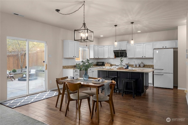 dining space featuring dark wood-type flooring and an inviting chandelier