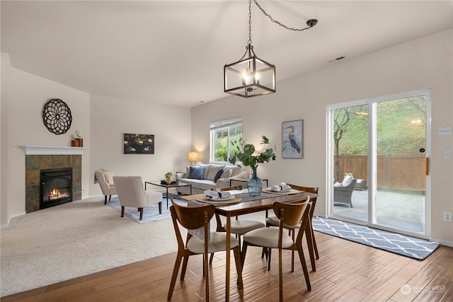 dining space with a tiled fireplace and hardwood / wood-style flooring