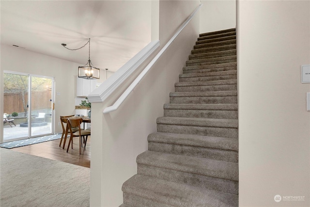 staircase with an inviting chandelier and hardwood / wood-style floors