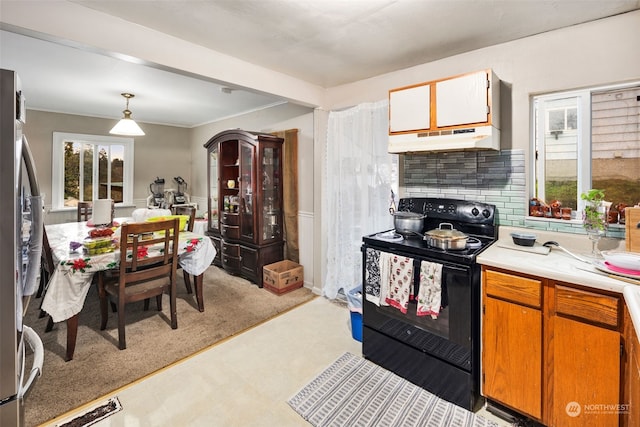 kitchen featuring light carpet, backsplash, pendant lighting, black range with electric stovetop, and stainless steel refrigerator