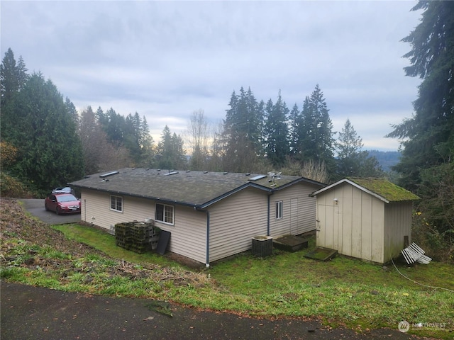 view of property exterior with central AC and a storage unit