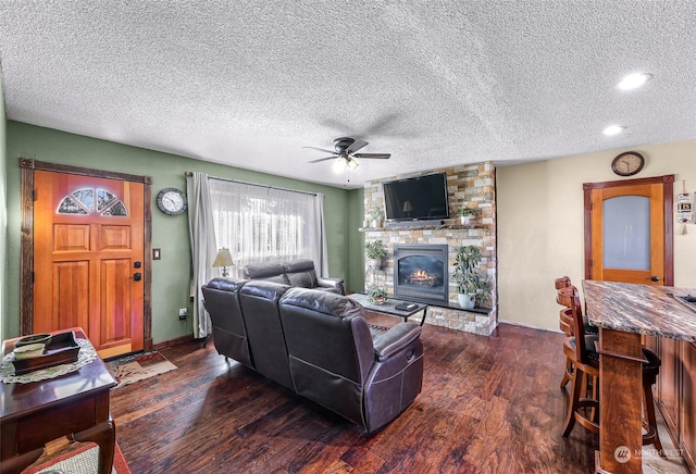 living room with dark hardwood / wood-style flooring, ceiling fan, a fireplace, and a textured ceiling