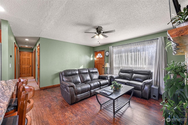 living room featuring a textured ceiling, ceiling fan, and dark wood-type flooring