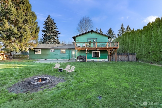 rear view of house featuring a fire pit, a deck, and a yard