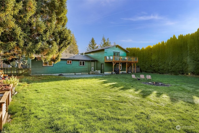 rear view of house with a yard, a deck, and an outdoor fire pit