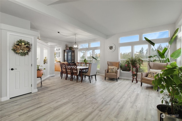 dining space featuring beamed ceiling, a chandelier, and light wood-type flooring