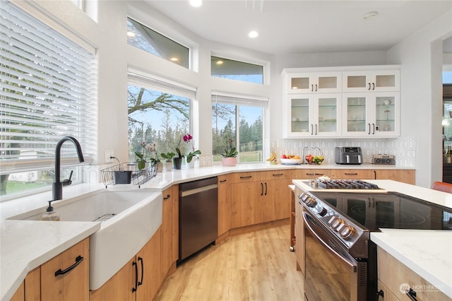 kitchen featuring tasteful backsplash, stainless steel appliances, sink, light hardwood / wood-style flooring, and white cabinetry