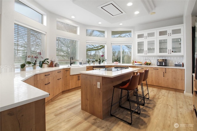 kitchen featuring a kitchen breakfast bar, sink, white cabinets, a center island, and light hardwood / wood-style floors