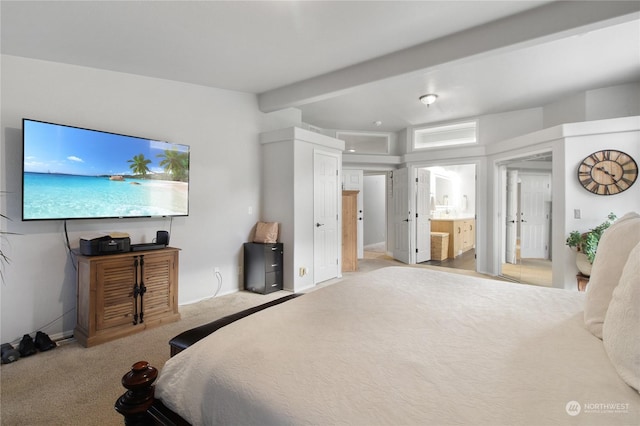 carpeted bedroom featuring beamed ceiling and ensuite bath