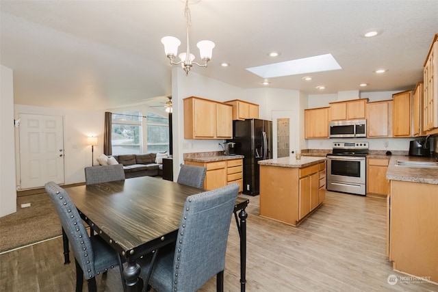 dining area featuring ceiling fan with notable chandelier, a skylight, light hardwood / wood-style floors, and sink