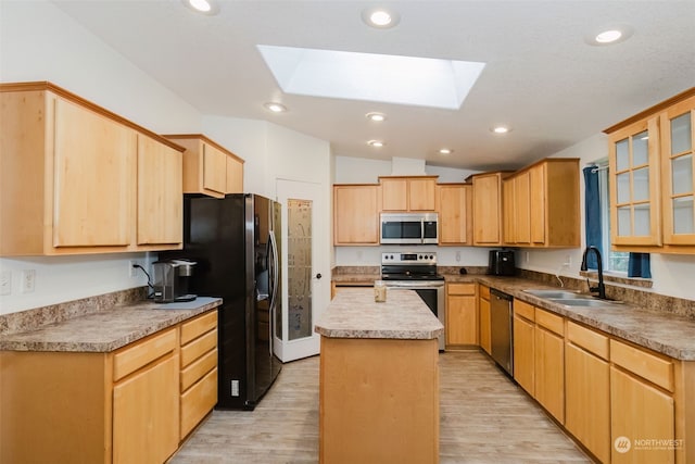 kitchen featuring appliances with stainless steel finishes, lofted ceiling with skylight, sink, a center island, and light hardwood / wood-style floors