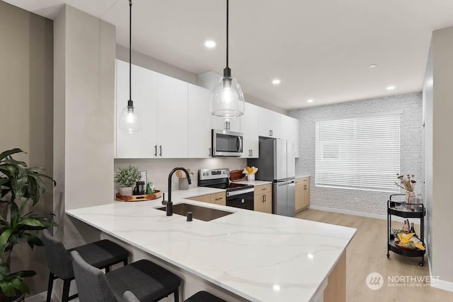 kitchen with white cabinets, light hardwood / wood-style floors, kitchen peninsula, and stainless steel appliances