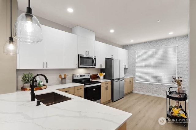 kitchen with white cabinetry, sink, light hardwood / wood-style floors, pendant lighting, and appliances with stainless steel finishes