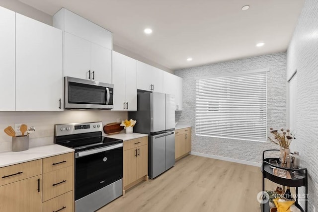 kitchen featuring white cabinets, light brown cabinets, light wood-type flooring, and appliances with stainless steel finishes