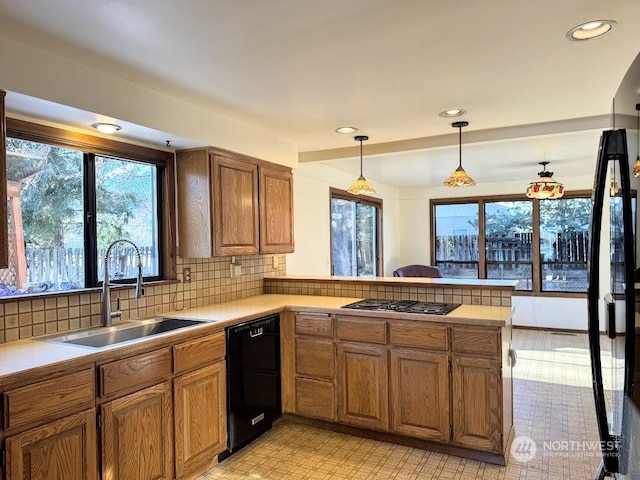 kitchen featuring pendant lighting, black appliances, sink, decorative backsplash, and kitchen peninsula