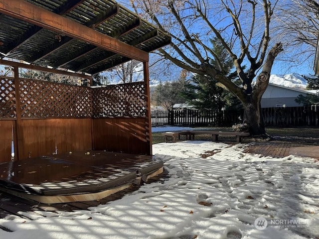 snow covered patio featuring a pergola and fence