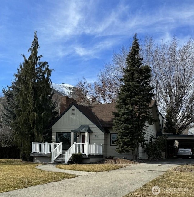 view of front of house with an attached carport, a front yard, driveway, and a shingled roof