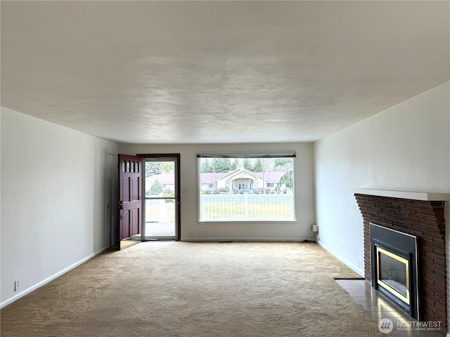 unfurnished living room with a brick fireplace, baseboards, and carpet floors