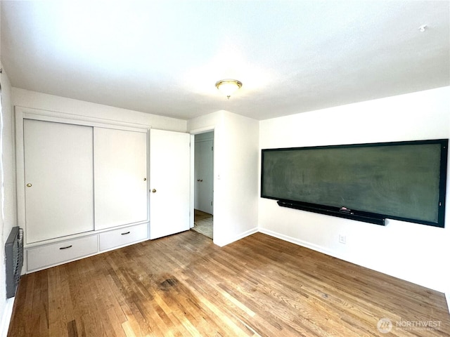 unfurnished bedroom with a closet, baseboards, and wood finished floors