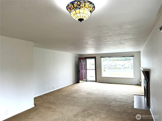 unfurnished living room featuring carpet flooring, a fireplace, and baseboards