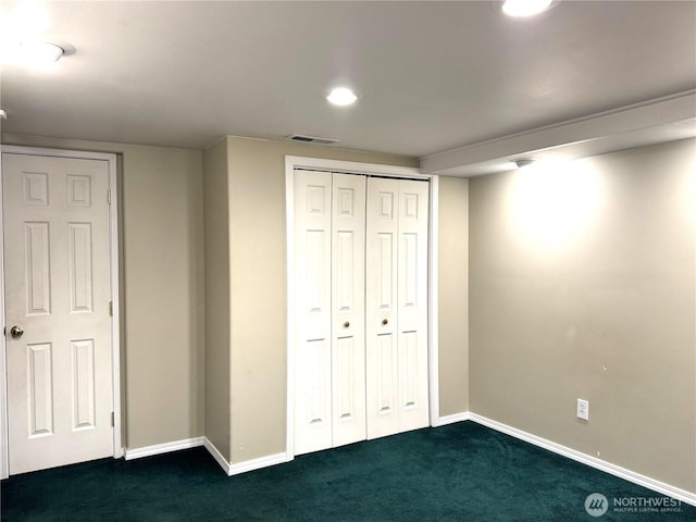 unfurnished bedroom featuring dark colored carpet, a closet, baseboards, and visible vents