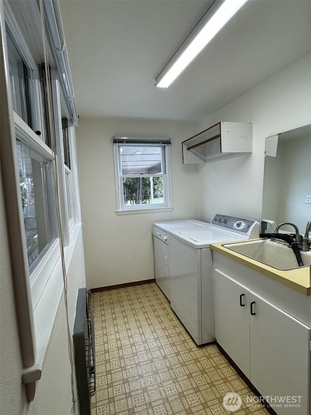 laundry room featuring washer and clothes dryer, light floors, baseboards, and a sink