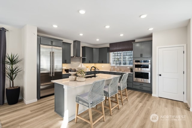 4021 Aberdeen Way NE, Renton, WA 98056 - kitchen featuring appliances with stainless steel finishes, wall chimney exhaust hood, light countertops, light wood-type flooring, and recessed lighting