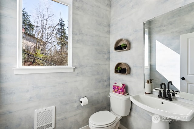 bathroom with sink, tile walls, and toilet