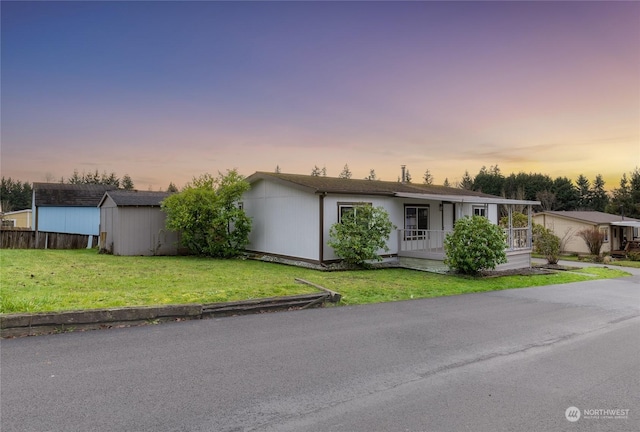 ranch-style home with covered porch, a storage unit, and a lawn