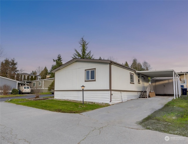 property exterior at dusk featuring a yard and a carport