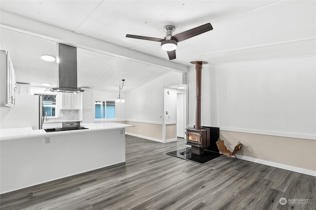 kitchen featuring a wood stove, kitchen peninsula, dark hardwood / wood-style floors, island range hood, and white cabinetry