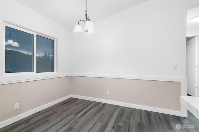 spare room featuring a chandelier and dark hardwood / wood-style floors