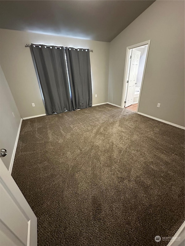 spare room with carpet and vaulted ceiling