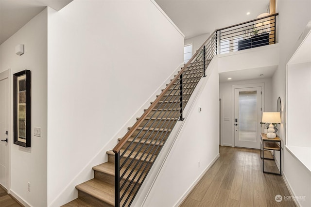 staircase with hardwood / wood-style flooring and a towering ceiling