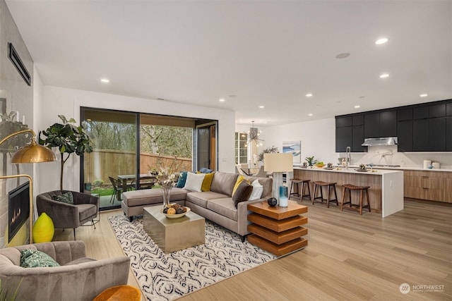 living room with a chandelier, light wood-type flooring, and sink