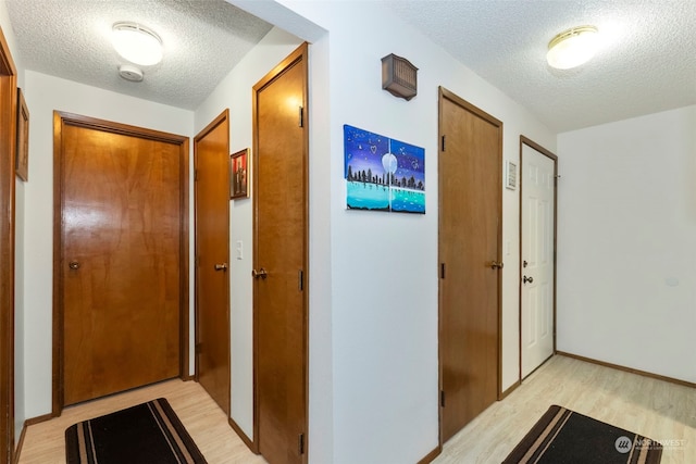 hall featuring light hardwood / wood-style flooring and a textured ceiling