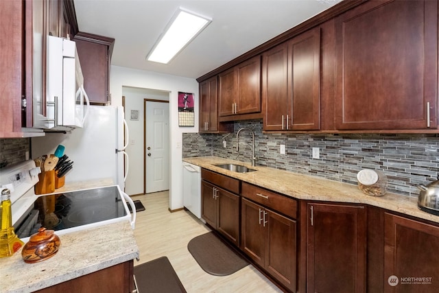 kitchen with white appliances, sink, decorative backsplash, light hardwood / wood-style floors, and light stone counters