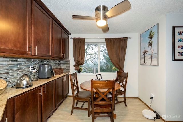 dining area with a textured ceiling, light wood-type flooring, and ceiling fan