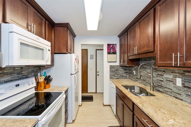 kitchen with light stone countertops, backsplash, white appliances, sink, and light hardwood / wood-style flooring