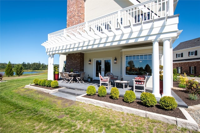 rear view of house with french doors, a pergola, a balcony, a yard, and a patio