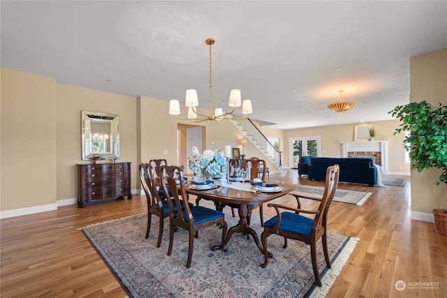 dining area featuring a fireplace, hardwood / wood-style floors, and a notable chandelier