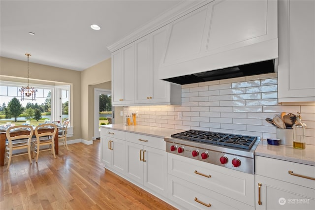 kitchen featuring white cabinetry, light hardwood / wood-style flooring, premium range hood, stainless steel gas stovetop, and decorative backsplash