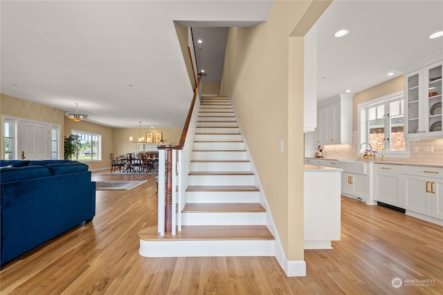 stairs featuring plenty of natural light, a chandelier, and hardwood / wood-style flooring