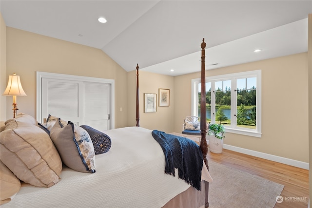 bedroom featuring a closet, vaulted ceiling, and light wood-type flooring