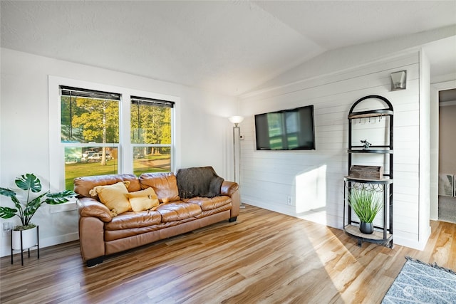 living room with hardwood / wood-style flooring, vaulted ceiling, and wood walls