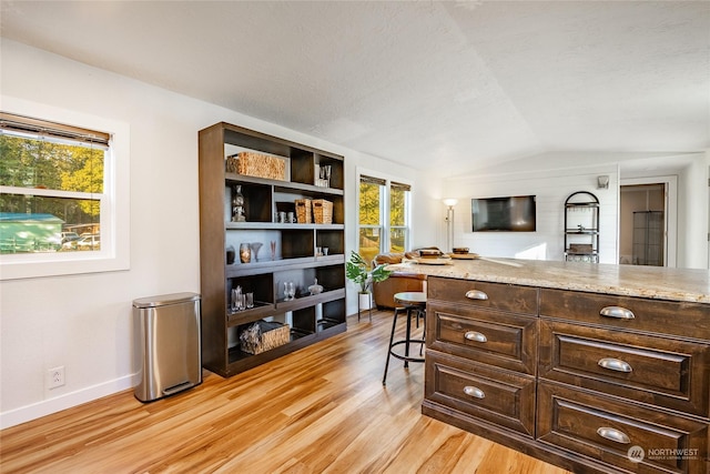 office space with a textured ceiling, vaulted ceiling, and light wood-type flooring